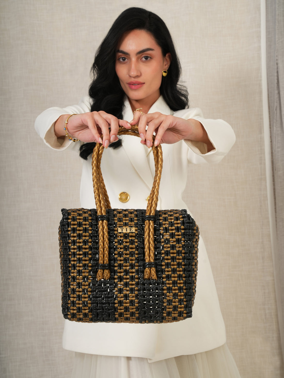 Woman holding a Closeweave Wire Basket (Black & Gold) against a neutral background