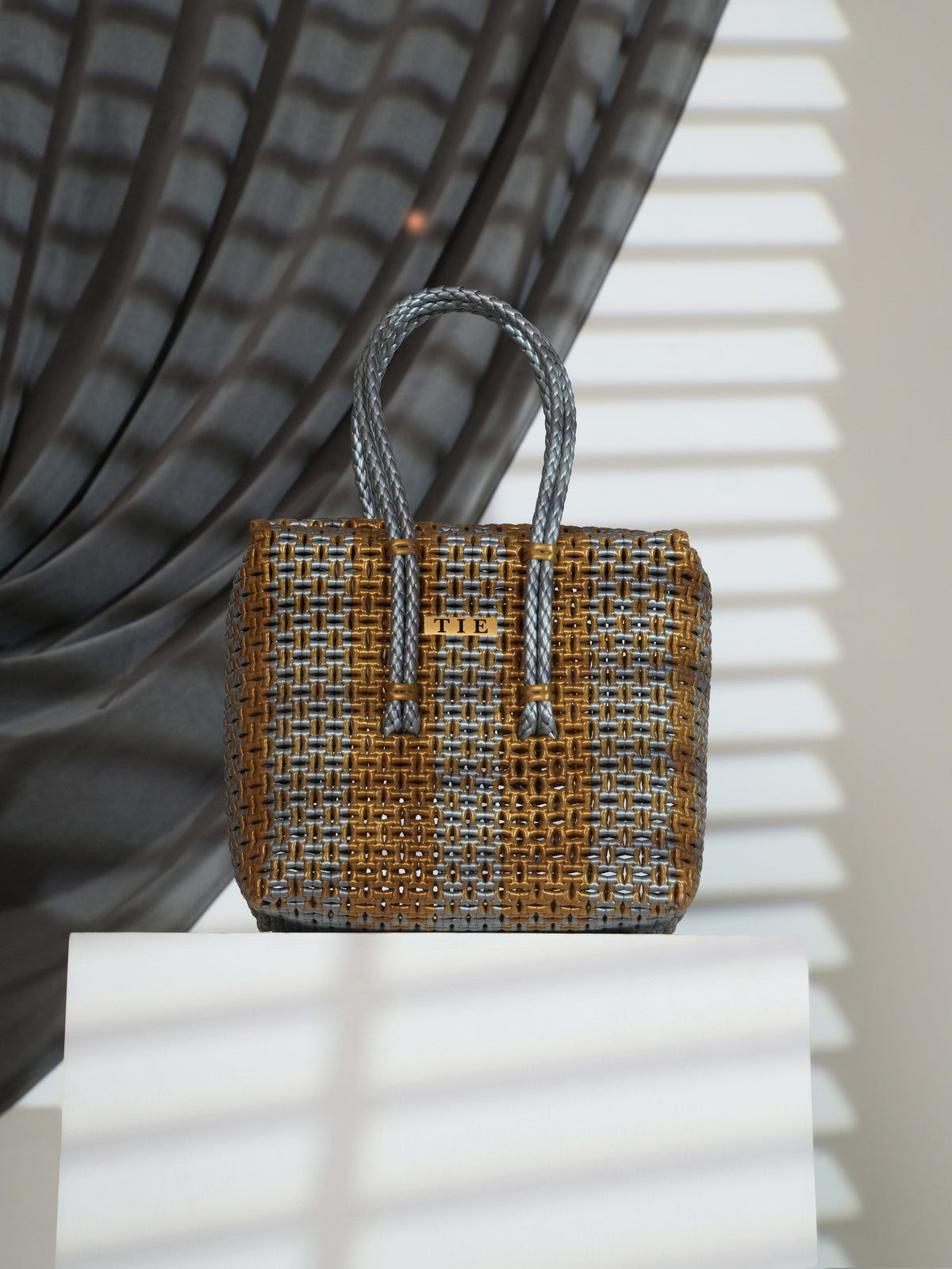 Closeweave Wire Basket with braided handle on a white surface with a textured gray background